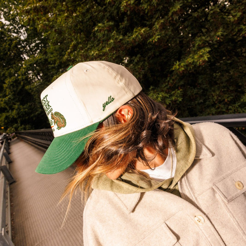Model twirling hair wearing Forest Park hat by yello salon